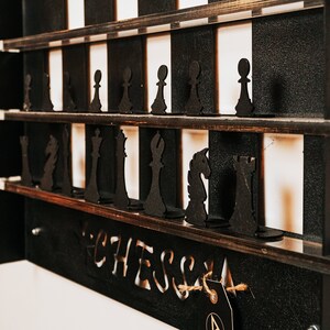 May include: A wooden chessboard with black and white squares. The board is filled with black chess pieces, including pawns, rooks, knights, bishops, a queen, and a king. The board is labeled "Chess" at the bottom.