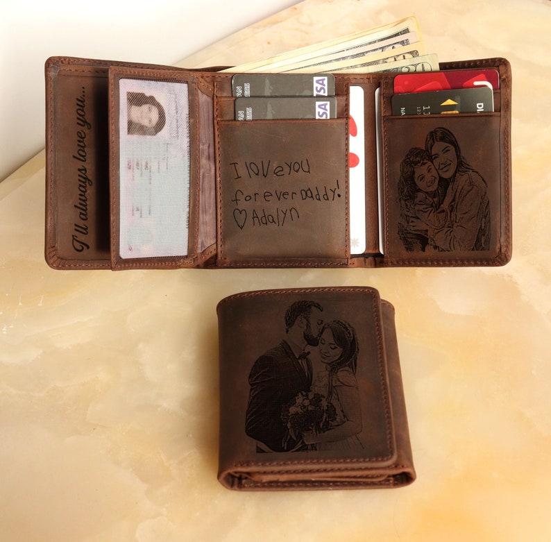 Puede incluir: Una cartera de cuero marr&oacute;n con un mensaje personalizado y grabados de fotos. El mensaje dice "Te amo para siempre pap&aacute;! Adalyn".