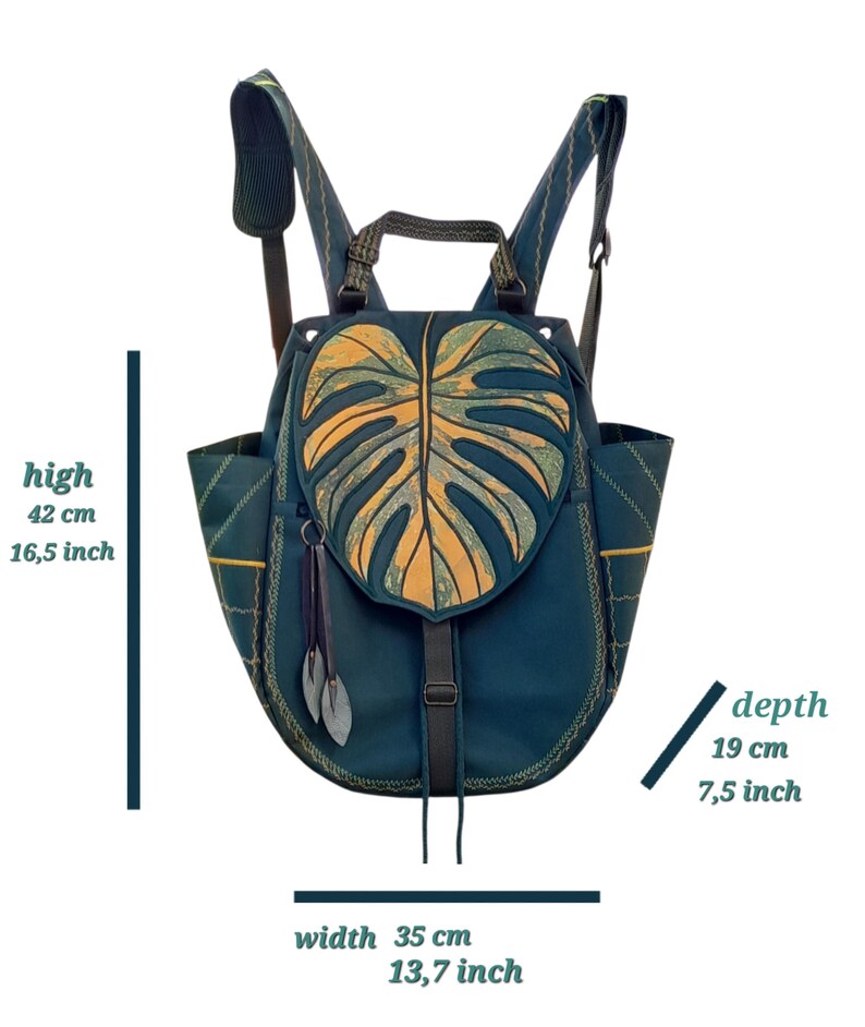 May include: A dark teal backpack featuring a large monstera leaf-shaped flap in yellow and green. It has adjustable shoulder straps, side pockets, and two leaf-shaped zipper pulls. Dimensions are 16.5 inches high, 13.7 inches wide, and 7.5 inches deep.