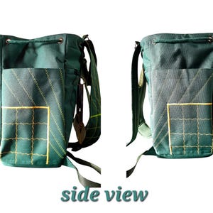 May include: A dark green canvas bucket-style backpack featuring a drawstring closure, adjustable shoulder straps, and an exterior pocket with yellow grid stitching and diagonal decorative lines. The bag includes side zippers and metal hardware.