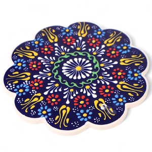 Könnte beinhalten: Ein blauer Keramik-Untersetzer mit einem farbenfrohen Blumenmuster. Der Untersetzer hat einen zentralen Kreis mit einer weißen Blume und grünen Blättern, umgeben von gelben, roten und blauen Blumen.