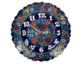 May include: A blue and white ceramic wall clock with a floral design. The clock has Roman numerals and a gold trim.