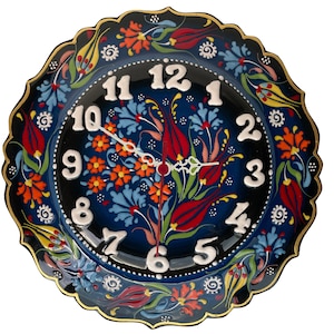May include: A round, blue and black ceramic wall clock with a white face and black numbers. The clock is decorated with colorful floral designs.