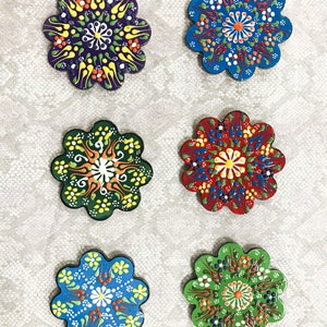 May include: Six colorful ceramic coasters with intricate floral designs. Each coaster features a different color scheme and pattern, including blue, green, red, and purple.