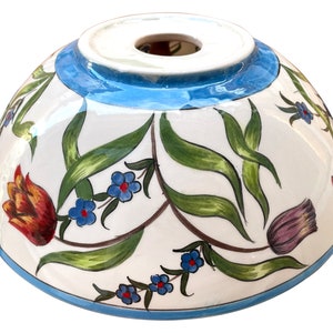 May include: A white ceramic bowl with a blue rim and floral design. The bowl features hand-painted tulips, leaves, and small blue flowers.