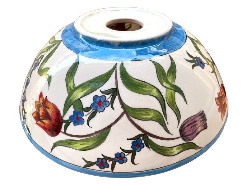 May include: A white ceramic bowl with a blue rim and floral design. The bowl features hand-painted tulips, leaves, and small blue flowers.