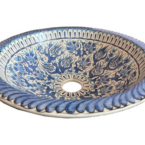 May include: A white ceramic sink with a blue and white floral design. The sink is round and has a small hole in the centre.