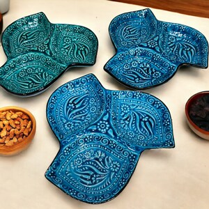 Puede incluir: Tres platos de servir de cerámica azul con intrincados patrones florales. Cada plato tiene tres secciones, perfecto para servir aperitivos o aperitivos.