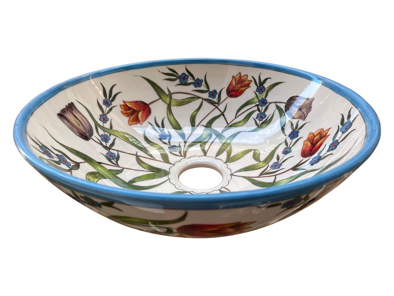 May include: A white ceramic oval sink with a blue rim and a floral design featuring red, orange, and blue flowers. The sink has a drain hole in the centre.