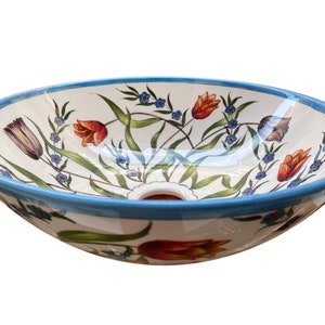 May include: A white ceramic sink with a blue rim and a floral design featuring red, orange, and yellow tulips and blue flowers.