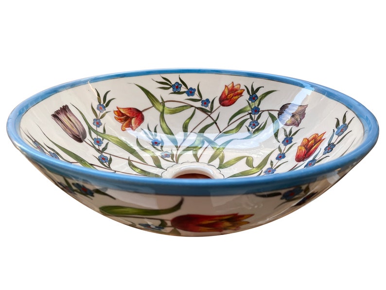 May include: A white ceramic sink with a blue rim and a floral design featuring red, orange, and yellow tulips and blue flowers.
