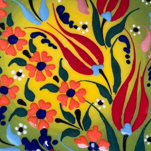 May include: A green and yellow ceramic plate with a floral design. The design features red, orange, blue, and white flowers and leaves.