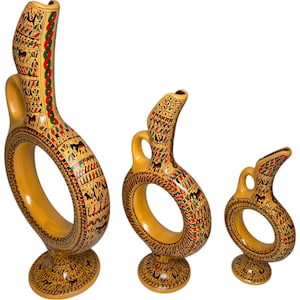 Puede incluir: Conjunto de tres jarrones de cerámica con asa de anillo. Los jarrones están decorados con un patrón geométrico colorido y son de color amarillo, rojo, verde y negro.