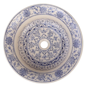 Pode incluir: Uma bacia de lavatório redonda de cerâmica branca suja com um orifício de drenagem central. É decorada com intrincados padrões florais e de volutas azuis. O design apresenta círculos concêntricos de motivos detalhados.