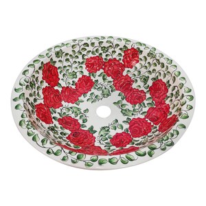 May include: White ceramic sink with a red and green floral design. The sink has a round shape and a single drain hole in the center.
