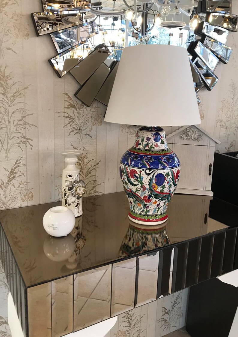 Peut inclure: Une lampe blanche avec un abat-jour blanc est pos&eacute;e sur une table en miroir avec un vase en c&eacute;ramique d&eacute;coratif aux motifs floraux color&eacute;s. Le vase est bleu, rouge, vert et blanc.