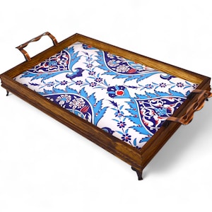 Puede incluir: Bandeja de madera para servir con un inserto de baldosas de cerámica con estampado floral. La baldosa presenta un fondo blanco con diseños florales azules, rojos y verdes. La bandeja tiene un marco de madera marrón oscuro y asas de color cobre.