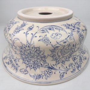 May include: A white ceramic bowl with a blue floral design. The bowl has a wide rim and a rounded bottom. The floral design is intricate and detailed, featuring flowers, leaves, and swirls.