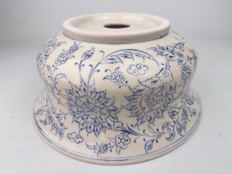 May include: A white ceramic bowl with a blue floral design. The bowl has a wide rim and a rounded bottom. The floral design is intricate and detailed, featuring flowers, leaves, and swirls.