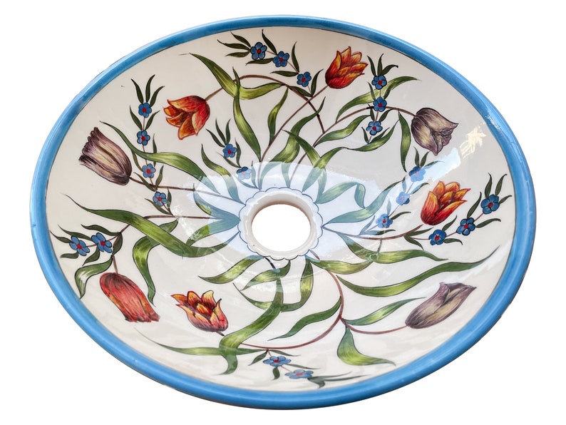 May include: A white ceramic sink with a blue rim and a floral design featuring tulips, leaves, and small blue flowers.