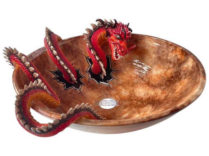 May include: An oval bathroom sink with a brown and tan mottled finish. A red dragon with white teeth and a long tail appears to be breaking through the sink's surface. The dragon's head and tail are visible, adding a fantasy theme.