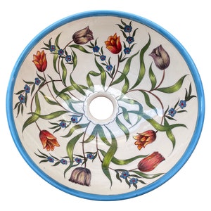 May include: A white ceramic sink with a blue rim and a floral design featuring tulips and small blue flowers. The sink is round and has a drain hole in the centre.
