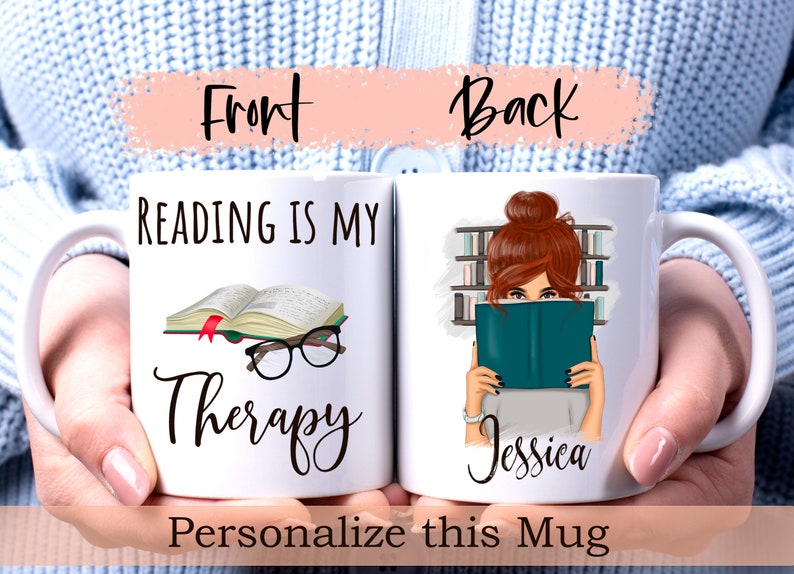 May include: White ceramic mug with a black and white illustration of a book and glasses with the text "Reading is my Therapy". The back of the mug has a colorful illustration of a woman reading a book with the text "Jessica".