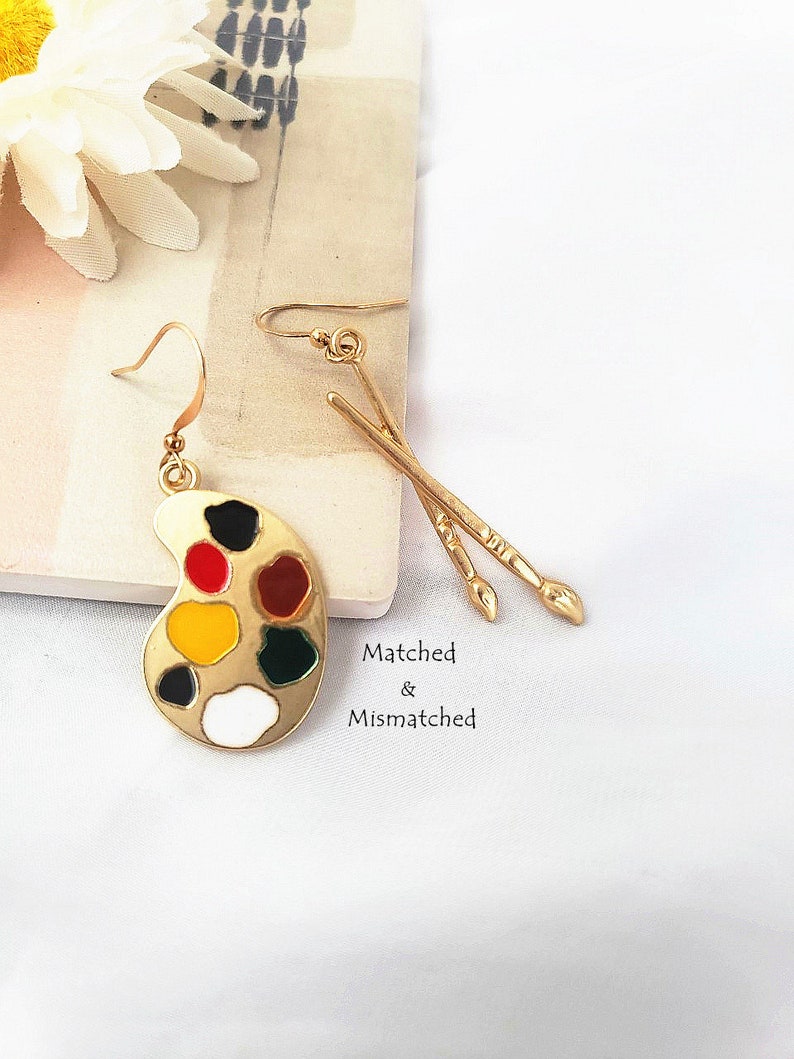 a pair of earrings come in paintbrush and paint pad shape polished with a golden color is the best gift for the artist