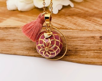 Stainless steel pregnancy bola with gold-plated copper bola ball and dried rose resin.