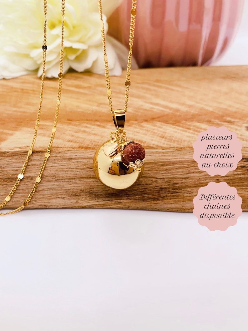May include: Gold necklace with a round charm and a small red stone. The charm has a textured surface. The text "plusieurs pierres naturelles au choix" and "Diff&eacute;rentes chaines disponible" is visible in the image.