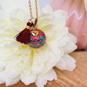 Bola de embarazo hecha a mano en baño de oro y resina con motivos de mosaico y su pequeño colgante de corazón.