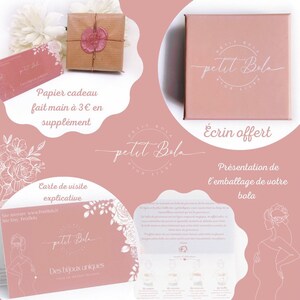 May include: A pink and white illustrated card with the text "Petit Bola" and "Des bijoux uniques" in a white circle. The card also includes the text "Papier cadeau fait main &agrave; 3&euro; en suppl&eacute;ment" and "Carte de visite explicative".