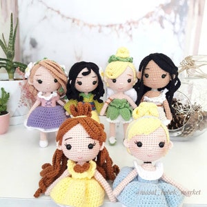 Könnte beinhalten: Eine Sammlung von sieben gehäkelten Puppen, die als Disney-Prinzessinnen verkleidet sind. Die Puppen tragen alle verschiedene farbige Kleider und haben unterschiedliche Frisuren. Die Puppen stehen alle auf einer weißen Oberfläche. @masal_bebek_market