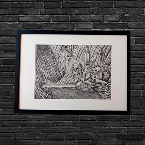 May include: Black and white framed art print depicting a detailed landscape with a castle, mountains, and a body of water. The artwork is in a detailed, etched style, with a black frame against a dark brick wall.