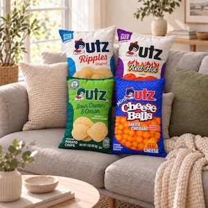 Op de afbeelding: Vier rechthoekige sierkussens ontworpen als Utz-snackzakken. De kussens zijn voorzien van afbeeldingen voor Ripples Original, Red Hot, Sour Cream & Onion en Mini Cheese Balls, inclusief het Utz-logo, productnamen en afbeeldingen van snacks.