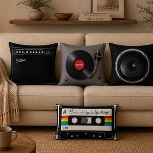 May include: A set of four decorative throw pillows featuring music-themed designs. Three square pillows display a black guitar amplifier, a gray vinyl record player, and a black speaker. One rectangular pillow shows a cassette tape with the text Music is my only drug.