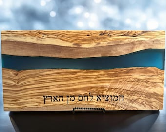May include: A wooden serving board with a blue resin inlay. The board has a natural wood grain pattern and the Hebrew text "הַמֶּרְכָּבָּה לֹּא תָּקוּם" is engraved on the bottom.