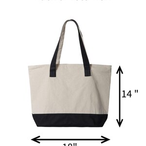 May include: Back view of a beige tote bag with black accents. The bag has black handles and a black bottom panel. The bag is 18 inches wide and 14 inches tall.