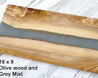 May include: A rectangular olive wood serving board with a grey resin inlay. The board measures 18 inches by 9 inches. The text "Olive wood and Grey Mist" is printed below the board.
