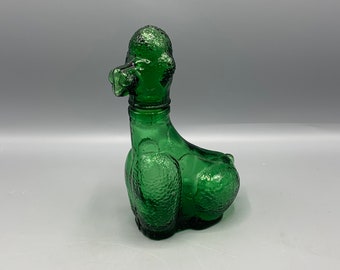 Peut inclure: Une bouteille en verre vert en forme de caniche. La bouteille a une surface texturée et est de style vintage.