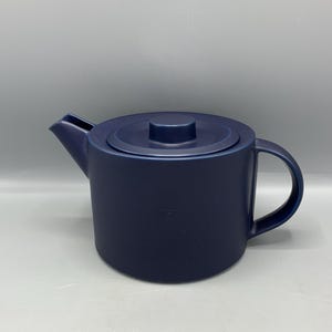 Può includere: Una teiera in ceramica blu scuro con un coperchio e un manico.