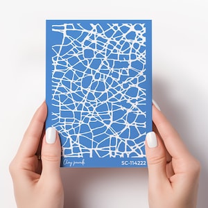Peut inclure: Pochoir à ongles bleu avec un motif craquelé blanc. Le pochoir est étiqueté "Clay Paradise" et "SC-114222".