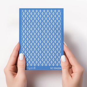 Könnte beinhalten: Eine blaue Folie mit Nagelkunst-Schablonen mit einem weißen geometrischen Muster. Die Folie trägt den Text "Clay Paradise" und "SC-104224".