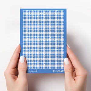 Op de afbeelding: Een sjabloon met blauw en wit geruit patroon. Het sjabloon heeft een blauwe rand en een herhalend geruit ontwerp. De tekst "Clay paradi" en "SC-209867" zijn zichtbaar op het sjabloon. Het sjabloon wordt door handen vastgehouden.