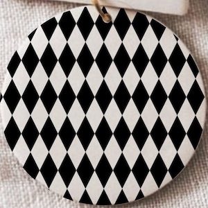 Pode incluir: Um ornamento redondo branco com um padrão de diamantes preto e branco.