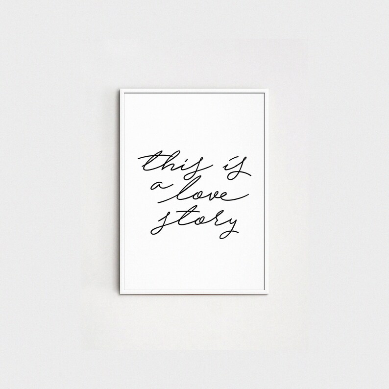 May include: A white framed print with black calligraphy that reads "this is a love story".