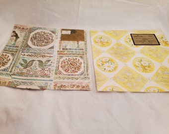 May include: Two sheets of vintage wrapping paper. One sheet features a white background with a repeating pattern of birds, flowers, and geometric shapes in shades of brown, green, and blue. The other sheet features a yellow background with a repeating pattern of white daisies and bouquets of flowers in shades of yellow and white.