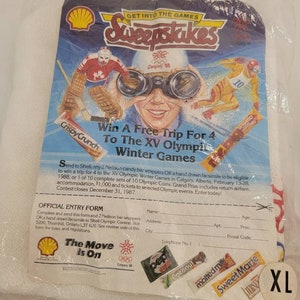 May include: A white t-shirt featuring a Shell Oil logo and a sweepstakes entry form for a trip to the 1988 Winter Olympics in Calgary. The form includes a picture of a hockey player and a skier. The text "Get into the Games Sweepstakes" is at the top of the form. The text "Win a Free Trip for 4 to the XV Olympic Winter Games" is in the center of the form. The text "The Move is On" is at the bottom of the form.