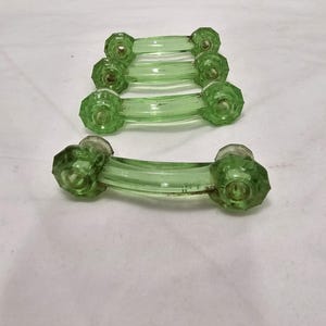 Peut inclure: Ensemble de cinq poignées de porte de placard en verre vert avec un design facetté. Les poignées sont empilées, la poignée du bas étant au point.