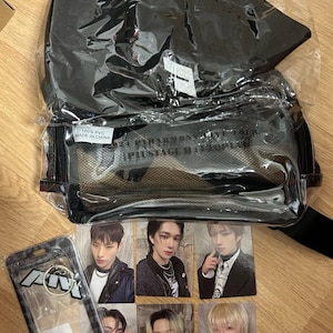 May include: A black and white photo card set featuring a group of men. The cards are displayed on a wooden surface with a black and clear plastic bag and a black and white key chain.
